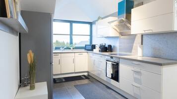 Een koelkast, een oven, een kookplaat, kookgerei, borden en bestek