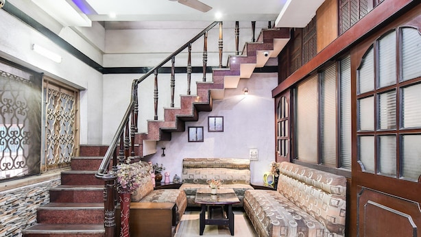 A staircase with ornate railings, a patterned sofa set, and a decorative vase. - Super Collection O Salt Lake (Bidhannagar)