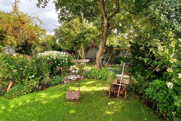 Un jardín con una mesa de madera, un letrero y una cesta de plantas.