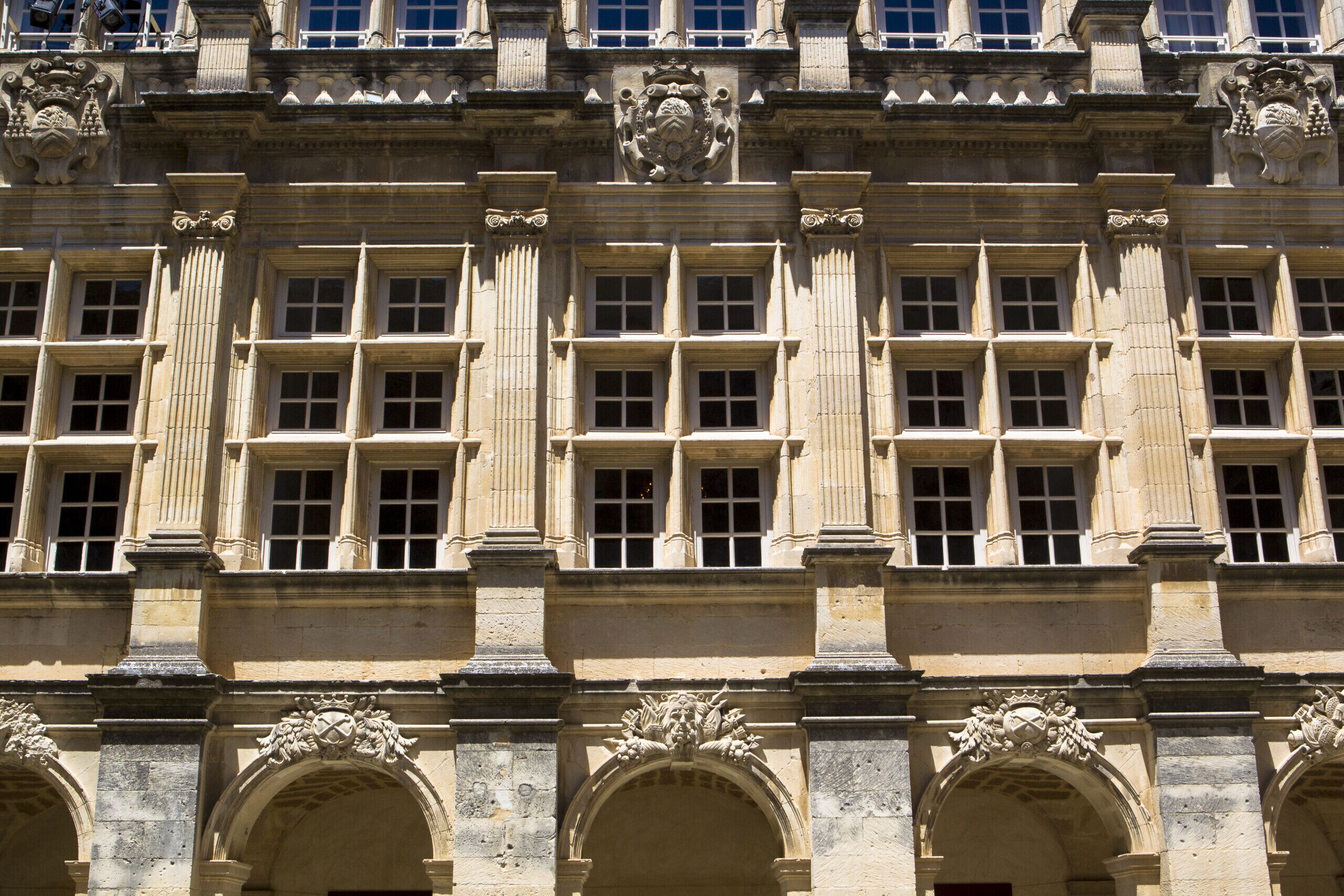 A historic building with a symmetrical facade, large windows, and ornate stone carvings.