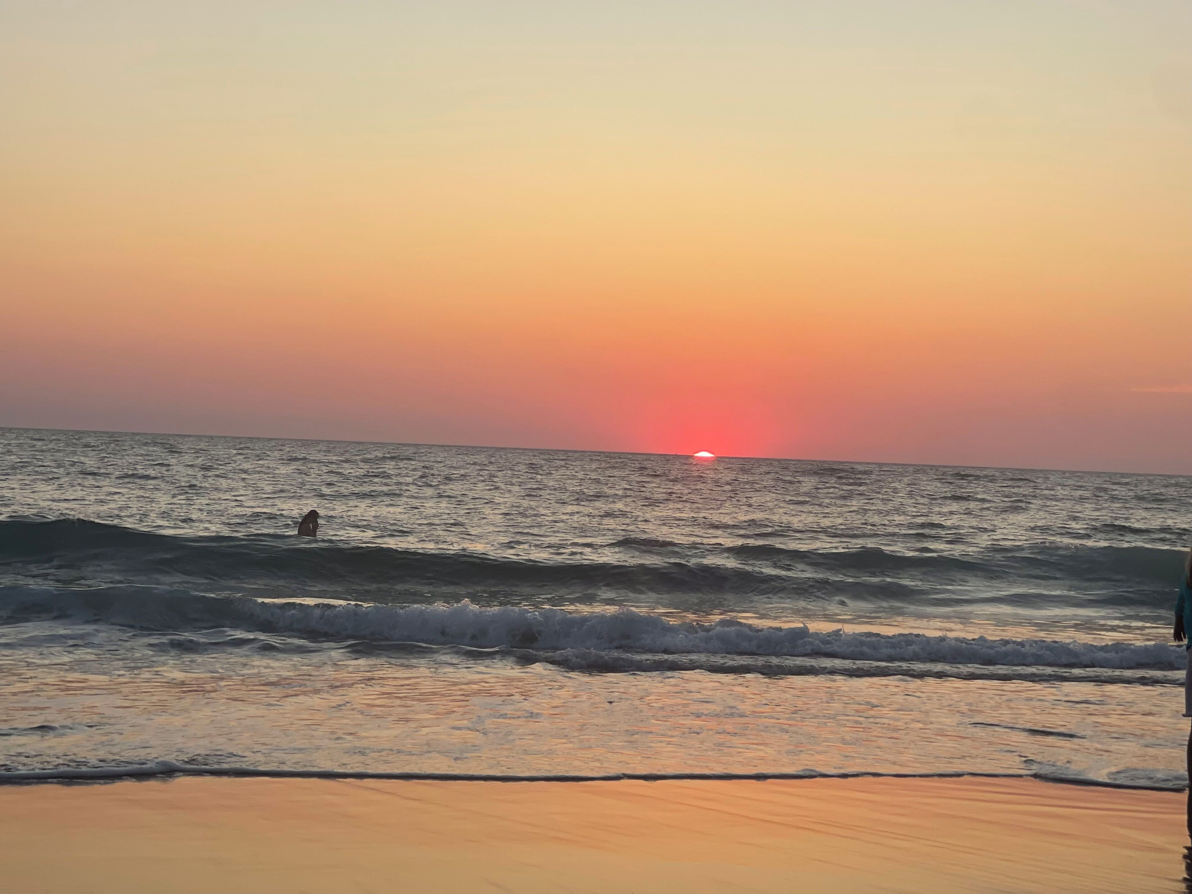 Une scène de plage avec des vagues et un coucher de soleil.