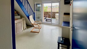 A spacious living area with a blue staircase, a sliding glass door leading to a patio, and a small table. - Carcans - 3 bedrooms near ocean + Parking (Carcans)