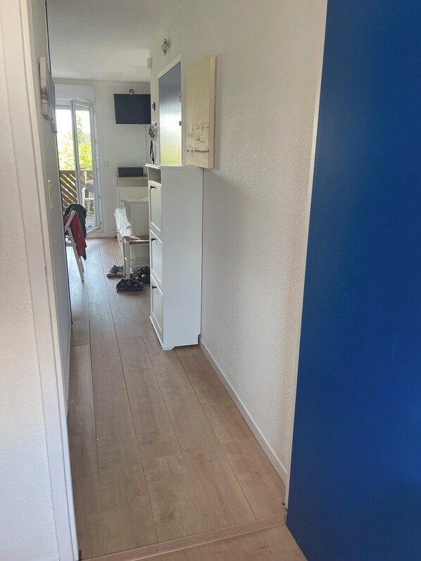 Un pasillo estrecho con un armario blanco, una pared azul y un piso de madera.