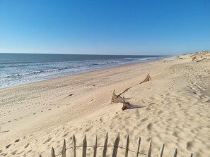 Una playa arenosa con una cerca de madera y un gran tronco de madera a la orilla.
