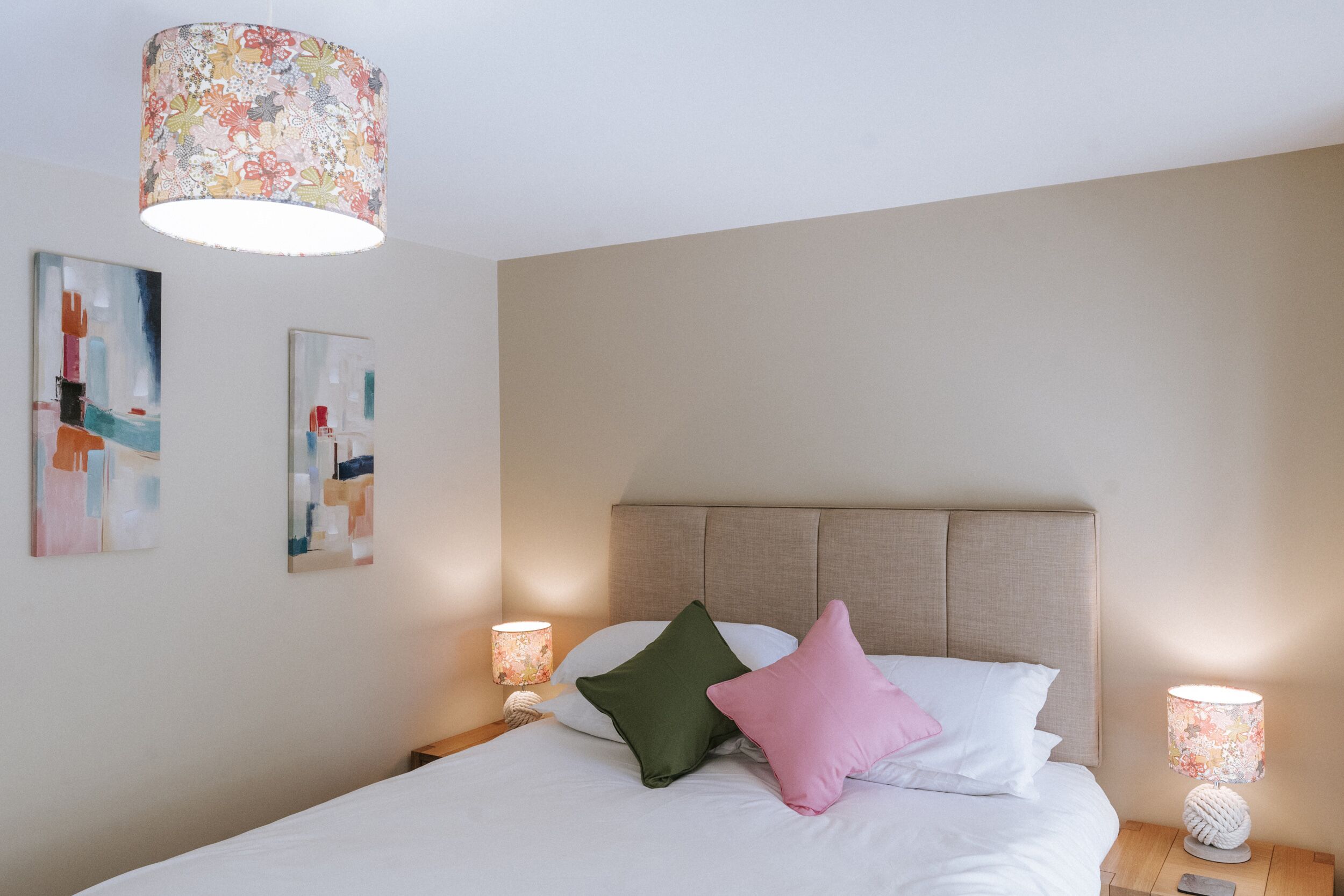 A neatly made bed with a headboard, two pillows, and a bedside lamp.