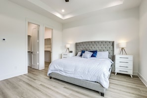 A bedroom with a bed, bedside tables, and a door leading to another room.
