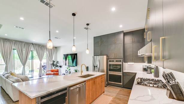 A modern kitchen with a central island, stainless steel appliances, and wooden cabinetry. - Modern & Spacious Home 3 Mi to Downtown Dallas! (Dallas)