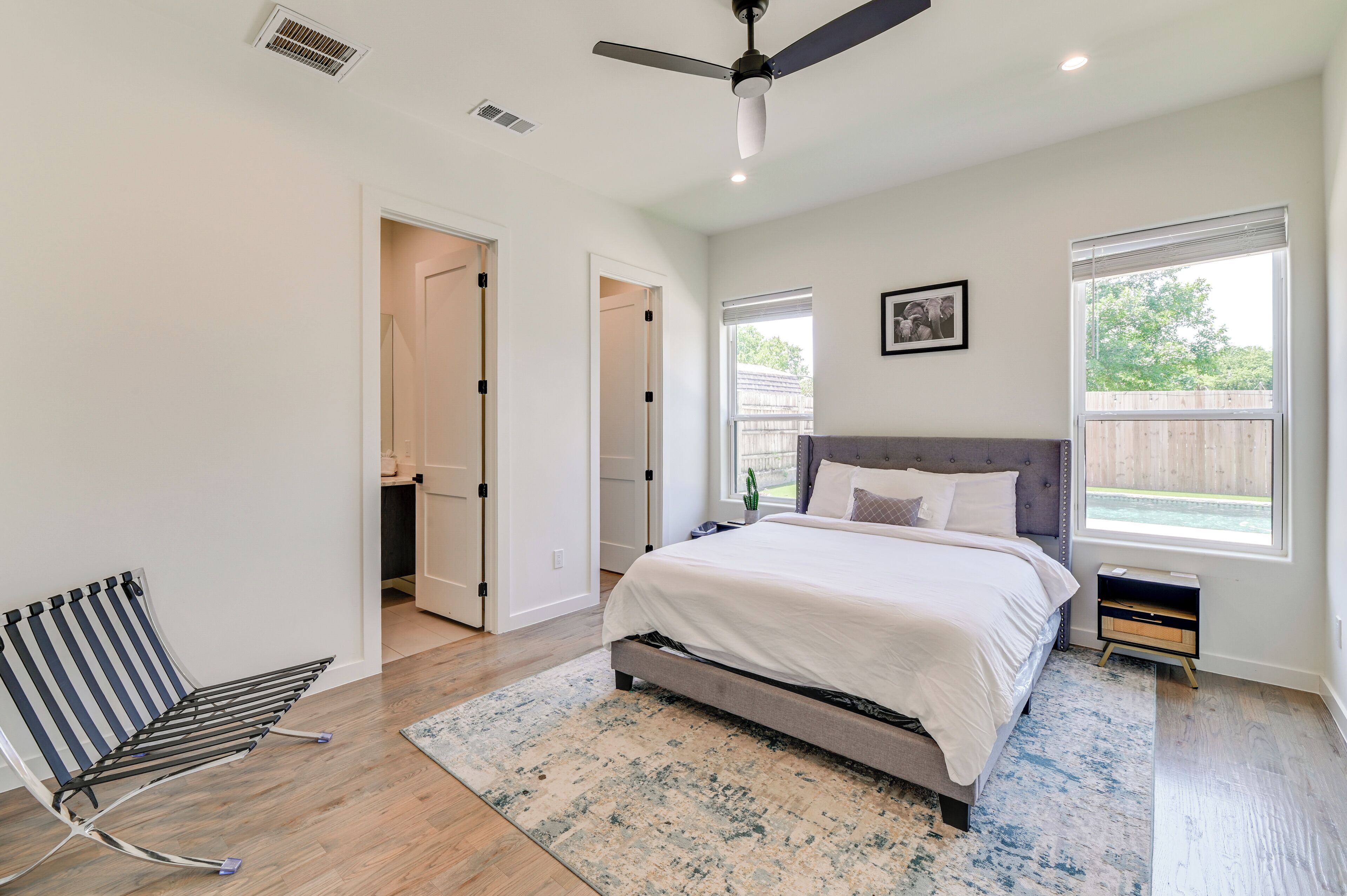 Un dormitorio con cama, ventilador de techo, ventana y puerta.