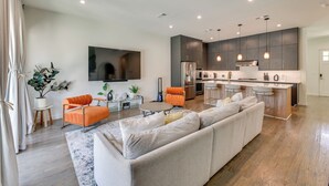 A modern living room with a large sectional sofa, a coffee table, and a TV mounted on the wall. - Modern & Spacious Home 3 Mi to Downtown Dallas! (Dallas)