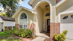 A residential house with a garage, a front porch with a curved roof, and a brick column. - 3 Mi to Disney: Family Home w/ Patio & Game Room (Kissimmee)