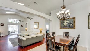A spacious living area with a dining table, chairs, a sofa, and a chandelier. - 3 Mi to Disney: Family Home w/ Patio & Game Room (Kissimmee)