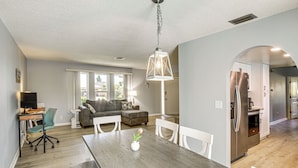 A modern kitchen with a dining area, wooden flooring, and a view of the outdoors. - Swim, Hike & Golf: Family Gem in Cape Coral! (Cape Coral)