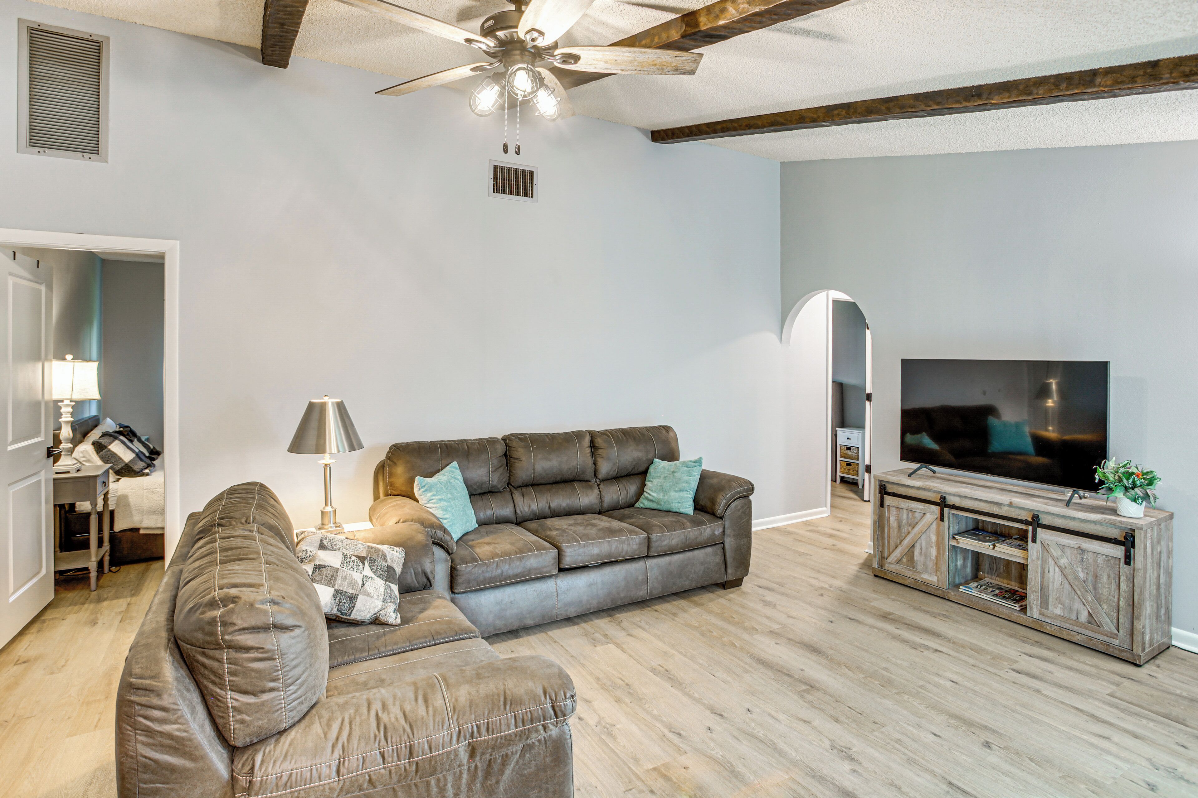 A living room with a brown leather sofa, a wooden entertainment center, and a ceiling fan.