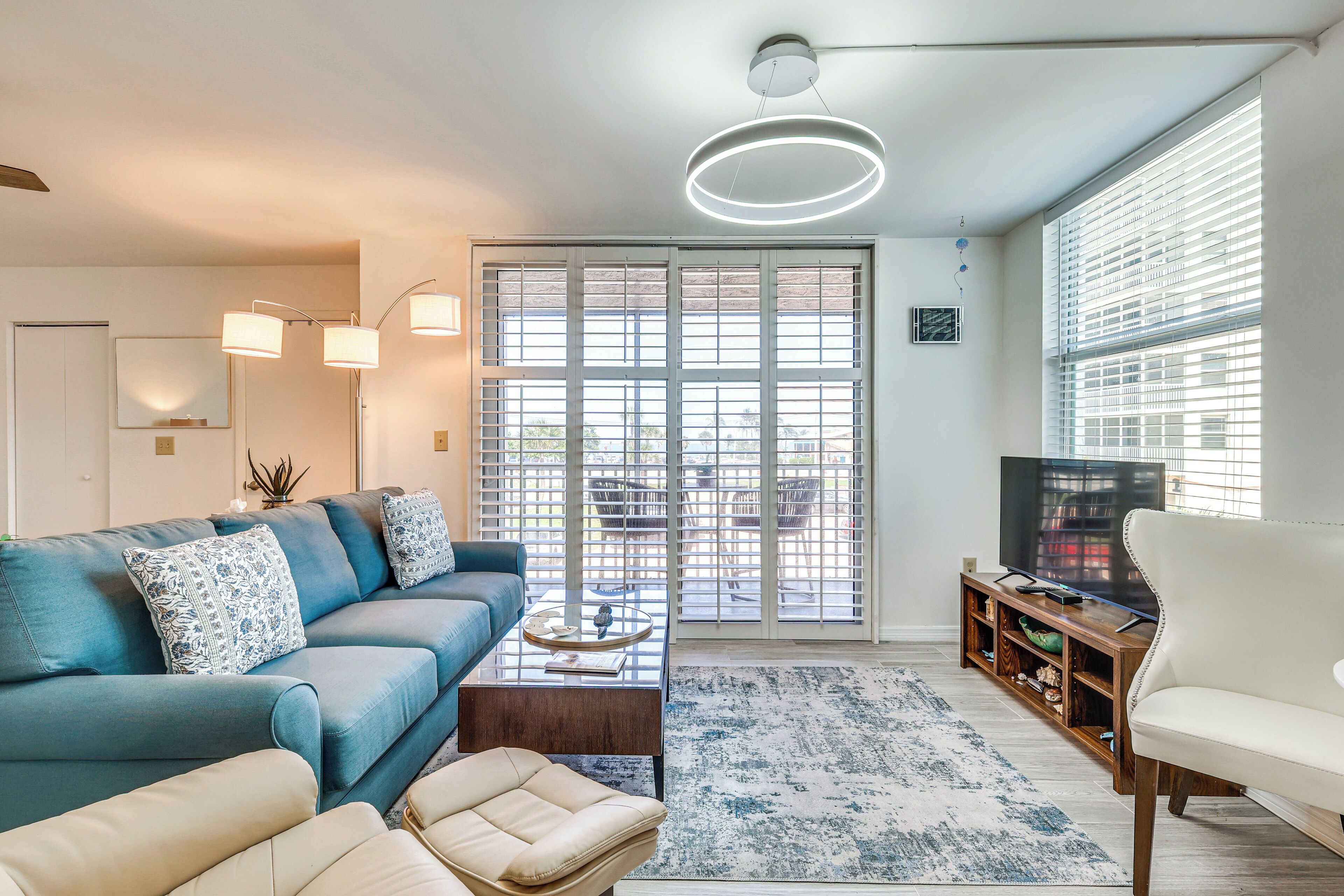 A living room with a blue sofa, a white armchair, a coffee table, and a TV stand.