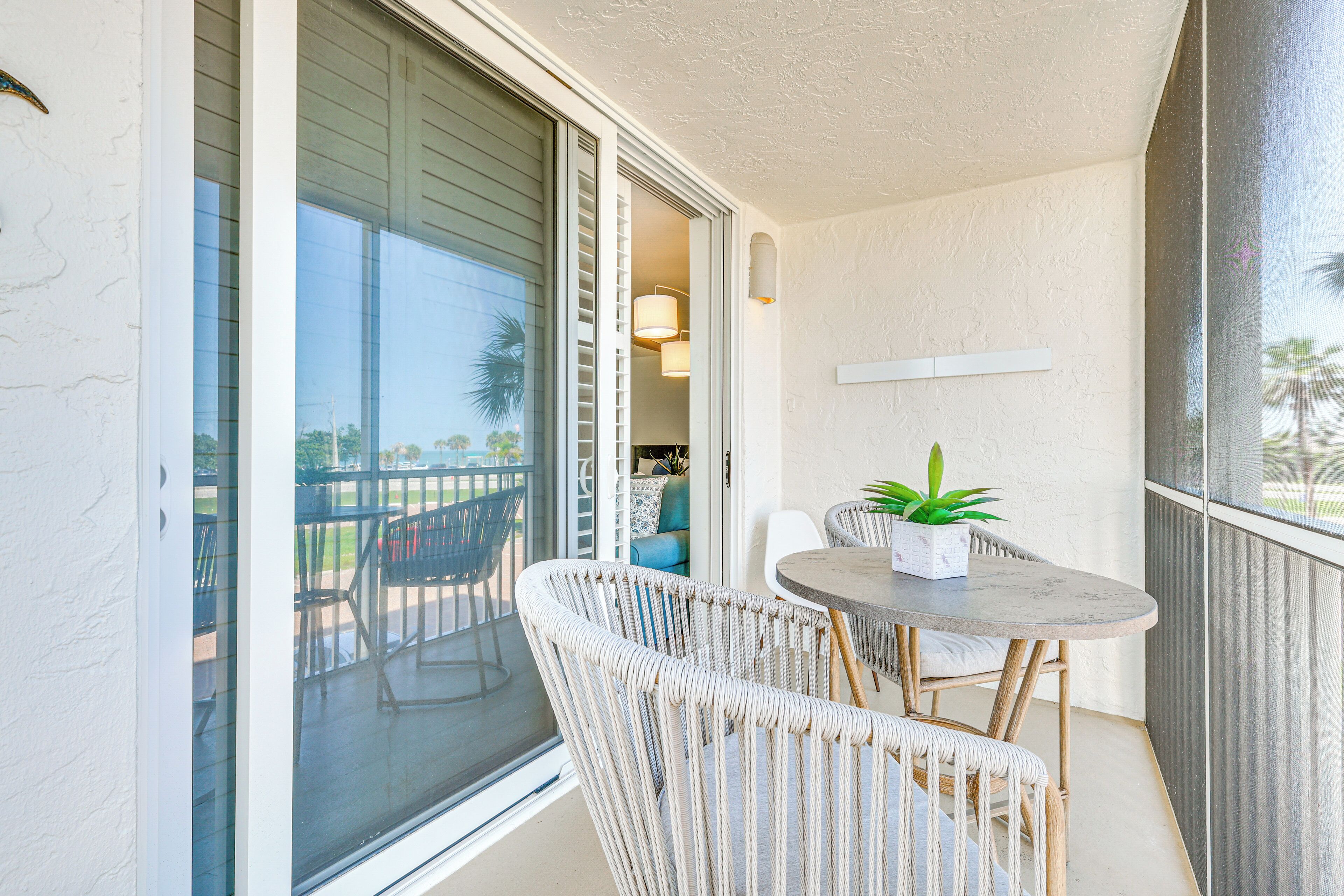 Un balcon avec des fauteuils en osier, une petite table ronde et une plante en pot.