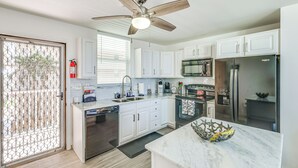 A modern kitchen with white cabinets, stainless steel appliances, and a marble countertop. - Walk to Gulf: Bonita Springs Studio w/ Pool! (Bonita Springs)