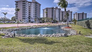 A residential area with high-rise buildings, a small pond, and a parking lot. - Walk to Gulf: Bonita Springs Studio w/ Pool! (Bonita Springs)