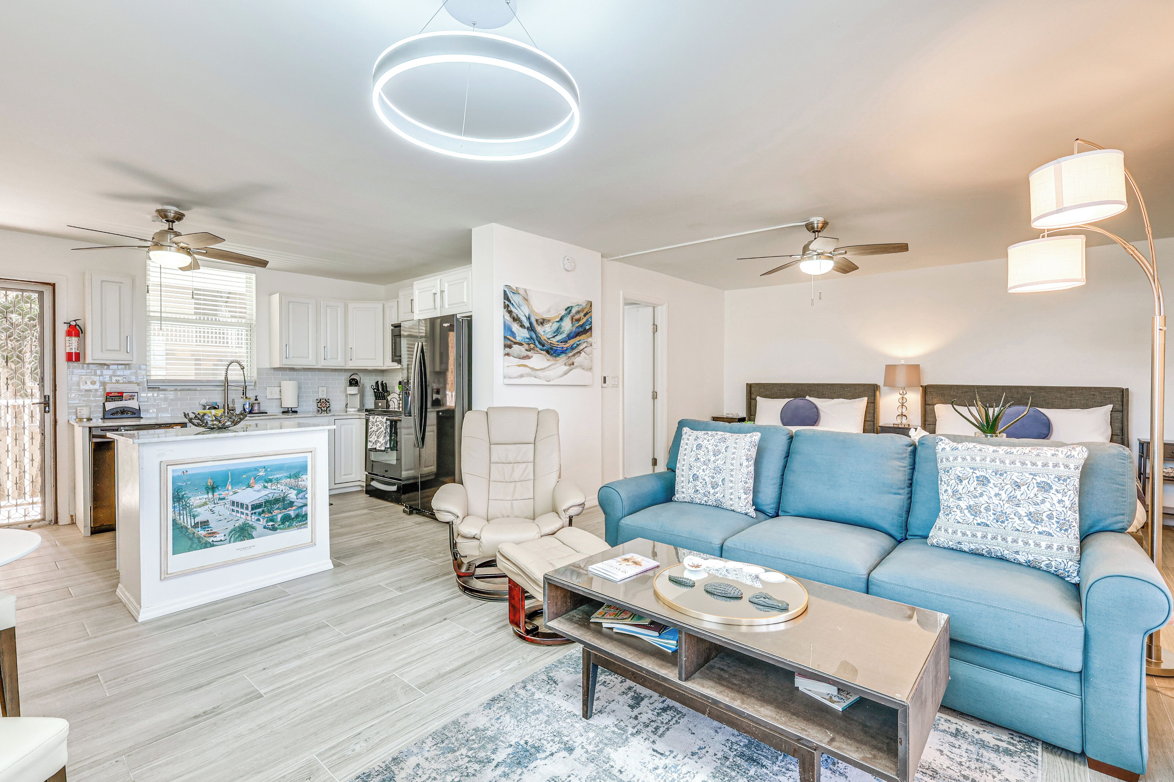 A modern living room with a blue sofa, a coffee table, and a ceiling fan.