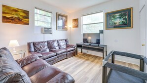 A modern living room with a leather sofa, a glass coffee table, and a flat-screen TV. - Walk to Food & Art: Condo in Historic Riverside (Jacksonville)