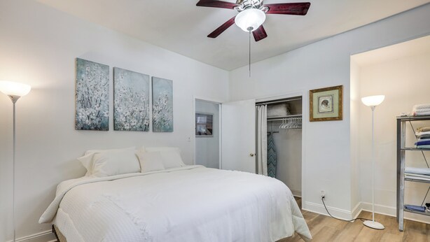 A bedroom with a bed, ceiling fan, artwork, and a walk-in closet. - Walk to Food & Art: Condo in Historic Riverside (Jacksonville)
