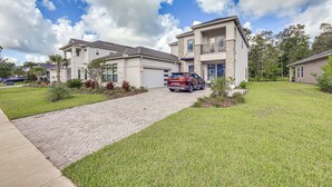 A residential area with modern houses, a paved driveway, and a parked SUV.
