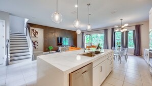 A modern kitchen with a central island, stainless steel appliances, and pendant lighting.