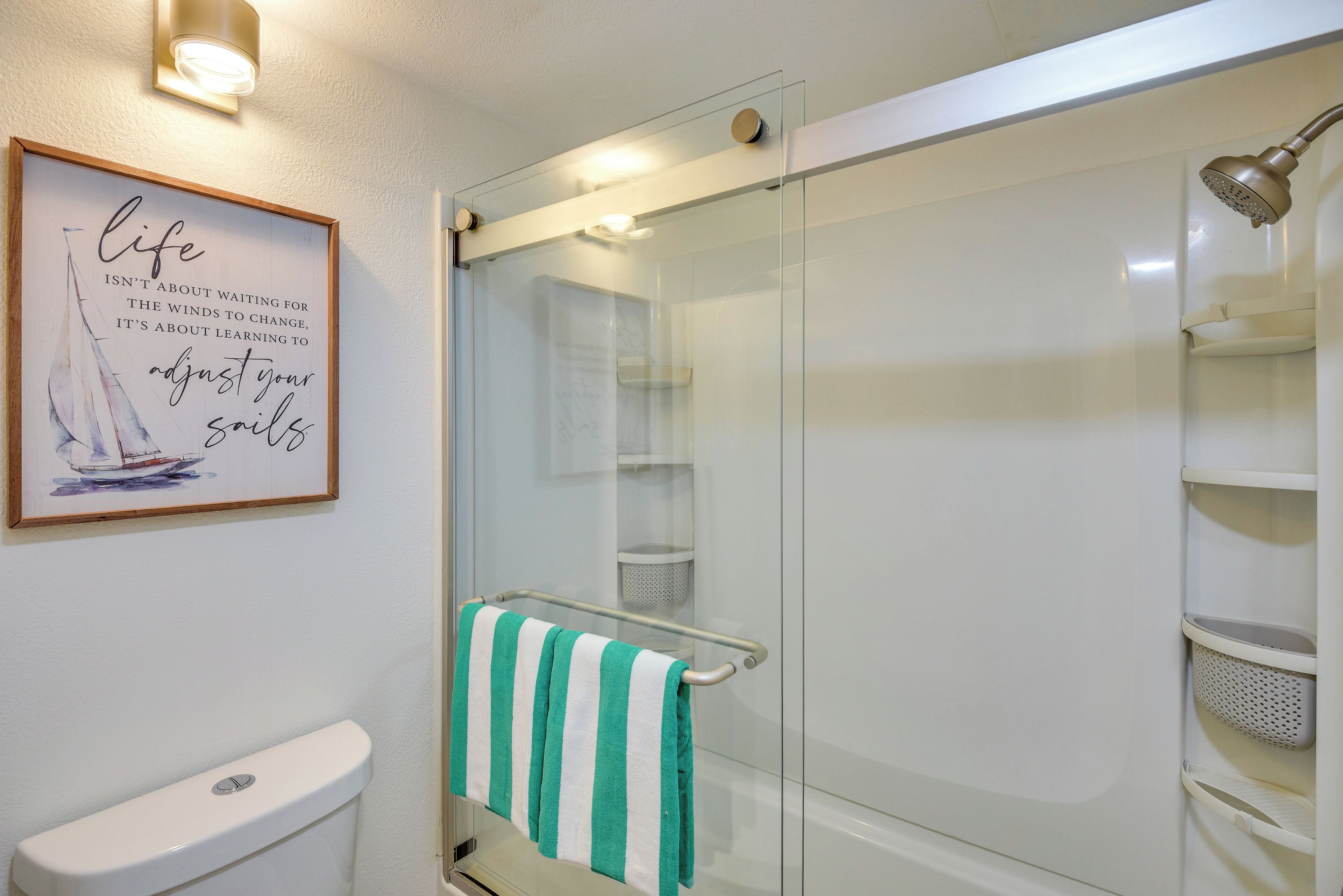 A bathroom with a glass shower enclosure, a toilet, and a towel rack with a striped towel.