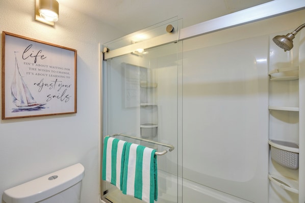 A bathroom with a glass shower enclosure, a toilet, and a towel rack with a striped towel.