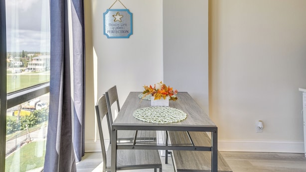 Un espace repas comprenant une table, des chaises, une décoration murale et une vue par la fenêtre.