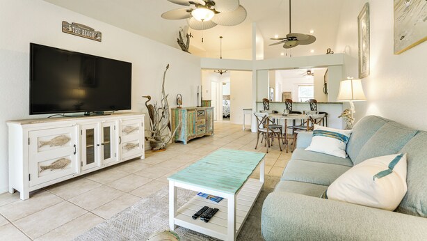 A spacious living room with a flat-screen TV, a white entertainment unit, a teal coffee table, and a grey sofa. - 5 Mi to Naples Beach - Getaway w/ Screened Lanai! (Naples)