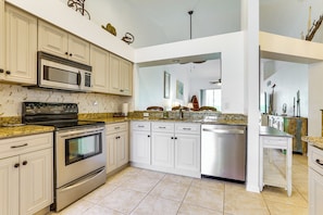 A modern kitchen with stainless steel appliances, white cabinetry, and a granite countertop.