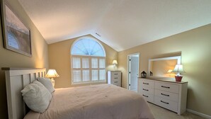 Un dormitorio con cama, cómoda, espejo, ventana y puerta.