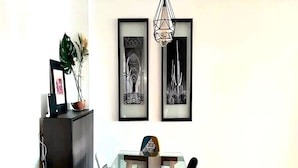 A dining area with a glass table, chairs, and framed artwork on the wall. - Casa Sahifa (Casablanca)
