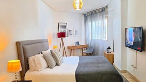 A modern hotel room with a large bed, a desk, a chair, a TV, and a lamp. - Casa Sahifa (Casablanca)
