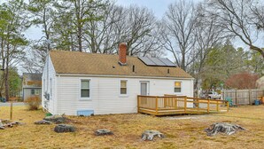 A single-story house with a wooden deck, a chimney, and solar panels on the roof. - Modern Home w/ Spacious Yard in Springfield! (Springfield)