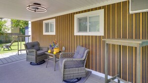 A covered patio area with wicker furniture, a table with yellow vases, and vertical striped wall panels. - 1 Mi to Dtwn: Renovated Retreat in Georgetown! (Georgetown)
