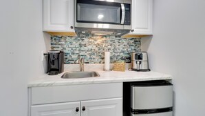 A compact kitchen with white cabinets, a stainless steel microwave, a coffee maker, and a refrigerator. - 1 Mi to Dtwn: Renovated Retreat in Georgetown! (Georgetown)