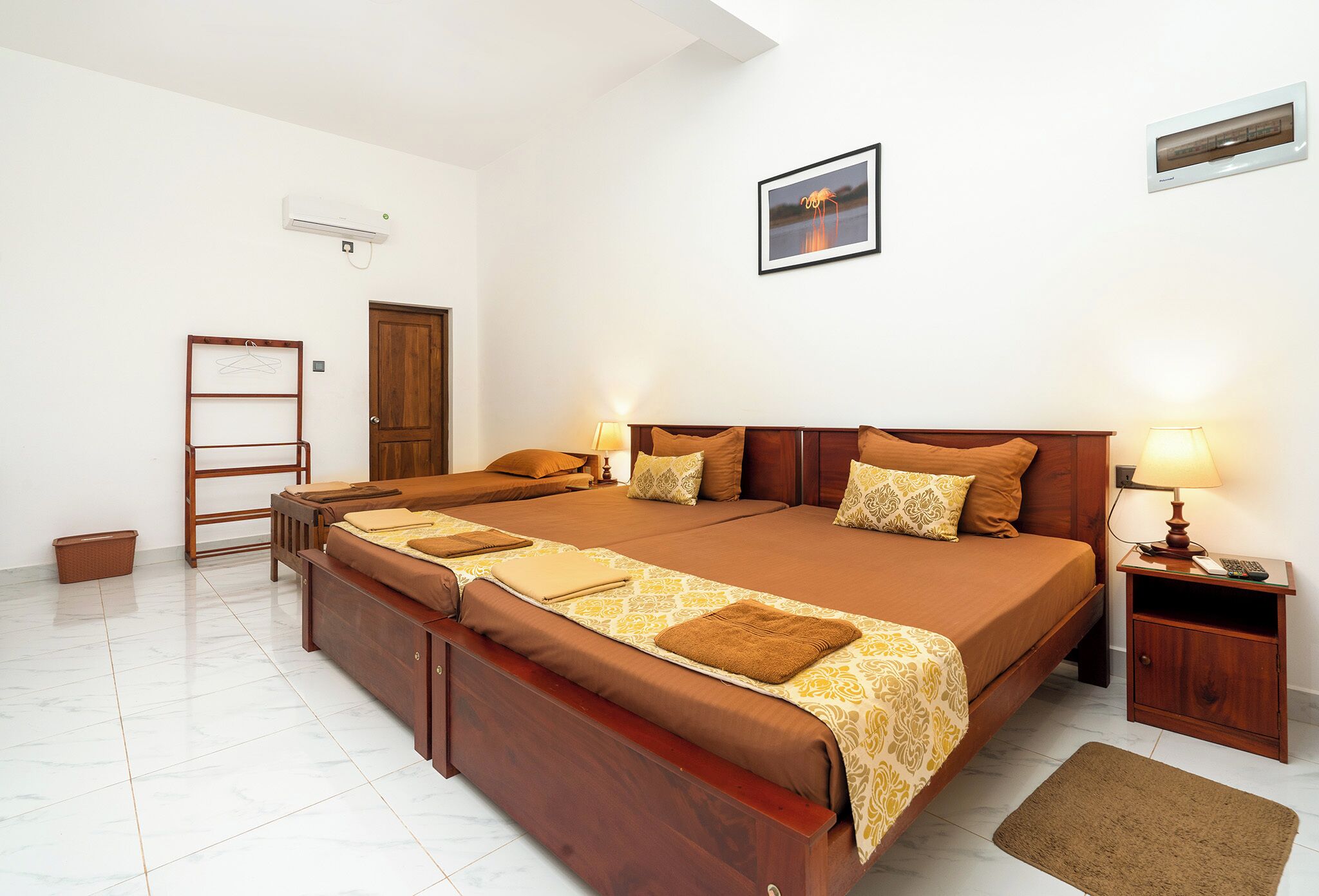 A spacious bedroom with a large bed, bedside tables, a wardrobe, and a hanging rack.