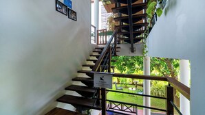 A staircase with wooden steps and metal railings, leading to an outdoor area with greenery and a view of a building. - Mailagama Cinnamon Residence (Sella Katharagama)