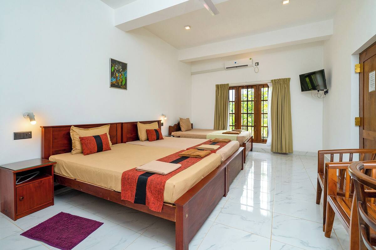 A hotel room with a large bed, a smaller bed, a desk, and a TV.