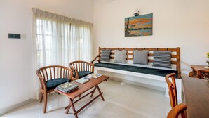 A living room with a wooden sofa, two wooden chairs, a small wooden table, and a painting on the wall. - Mailagama Cinnamon Residence (Sella Katharagama)