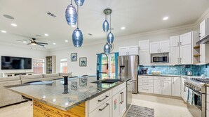 A modern kitchen with white cabinets, stainless steel appliances, and a large island with a granite countertop. - 'the Blue Oasis' Group Getaway! Walk to Jax Beach (Jacksonville Beach)