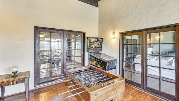 A room with a foosball table, a television, and a window with a view of a bed. - Stunning Valley & Mtn Views: Elegant Temecula Home (Temecula)
