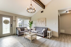 Een woonkamer met een grijze bank, een houten salontafel en een kroonluchter.