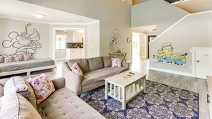 A living room with a grey sofa, a white coffee table, and a patterned rug. - Disney-themed Home: Swim, BBQ & Explore Kissimmee! (Kissimmee)
