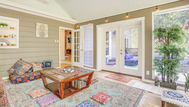 A cozy living room with a coffee table, patterned rugs, and a large window offering a view of the outdoors.