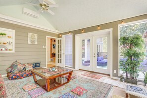 A cozy living room with a coffee table, patterned rugs, and a large window offering a view of the outdoors. - 6 Mi to Stone Mountain Park: Home w/ Deck! (Snellville)
