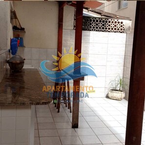 A tiled corridor with a tiled floor, a wooden column, and a potted plant.