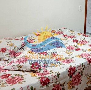A bed with a floral bedspread and a sun design. - Apt° Meridien 103 (Praia do Morro Guarapari)