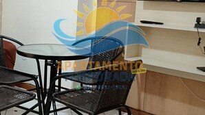 Una habitación pequeña con un televisor montado en la pared, una mesa con sillas y un mueble debajo del televisor.